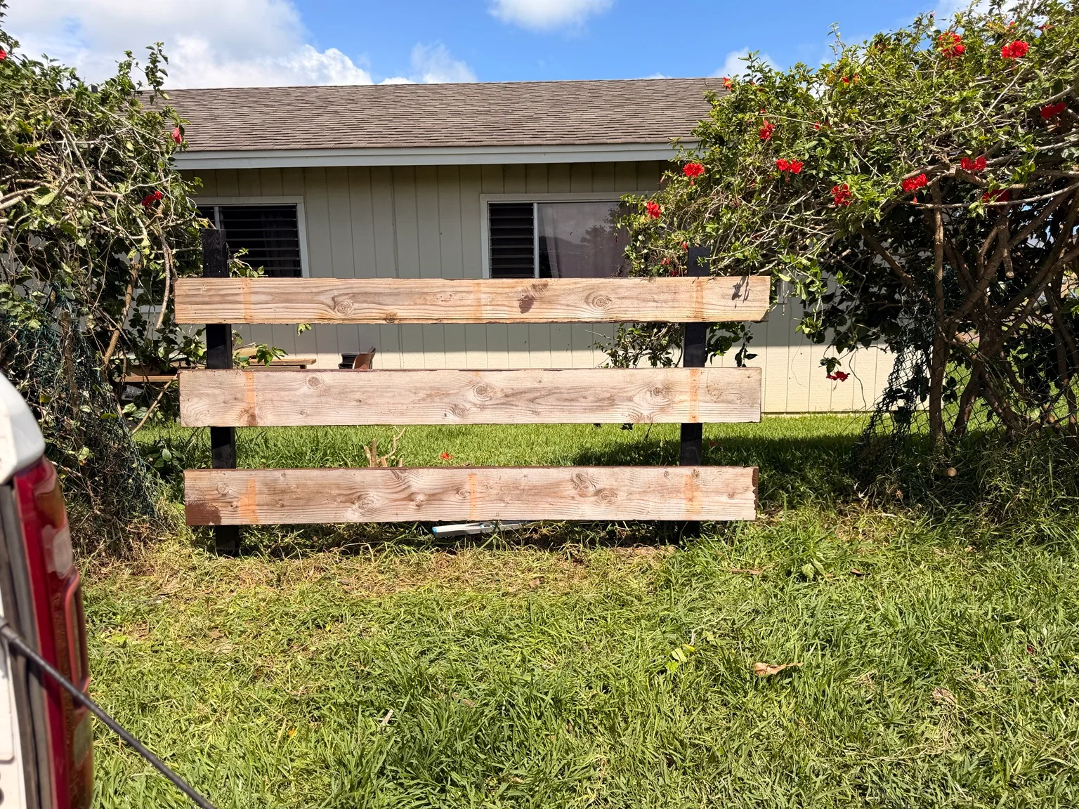 Repaired timber rail fence beside a Kauaʻi home