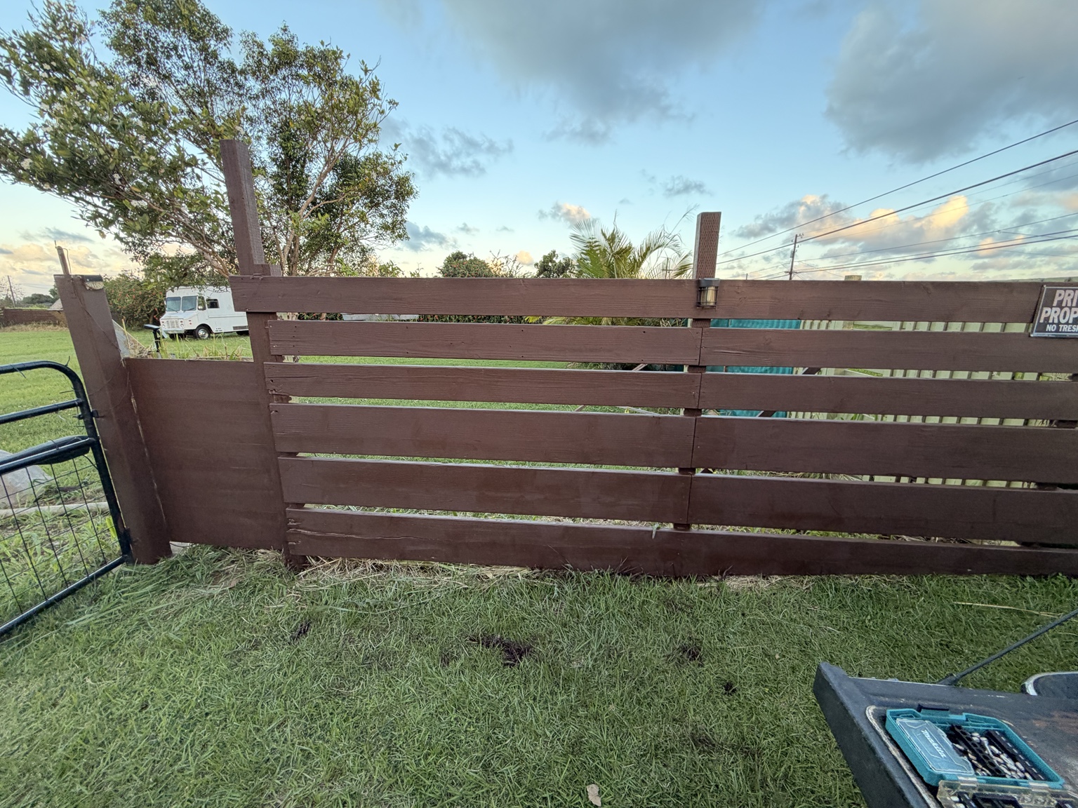 Brown horizontal timber fence beside a Kauaʻi property entrance
